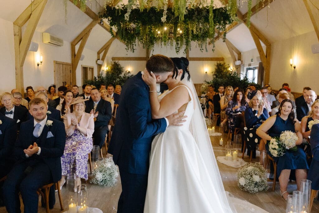 Bride and groom have their first kiss at the end of their wedding ceremony at the River Barn, Lancashire, by Nessworthy Pictures