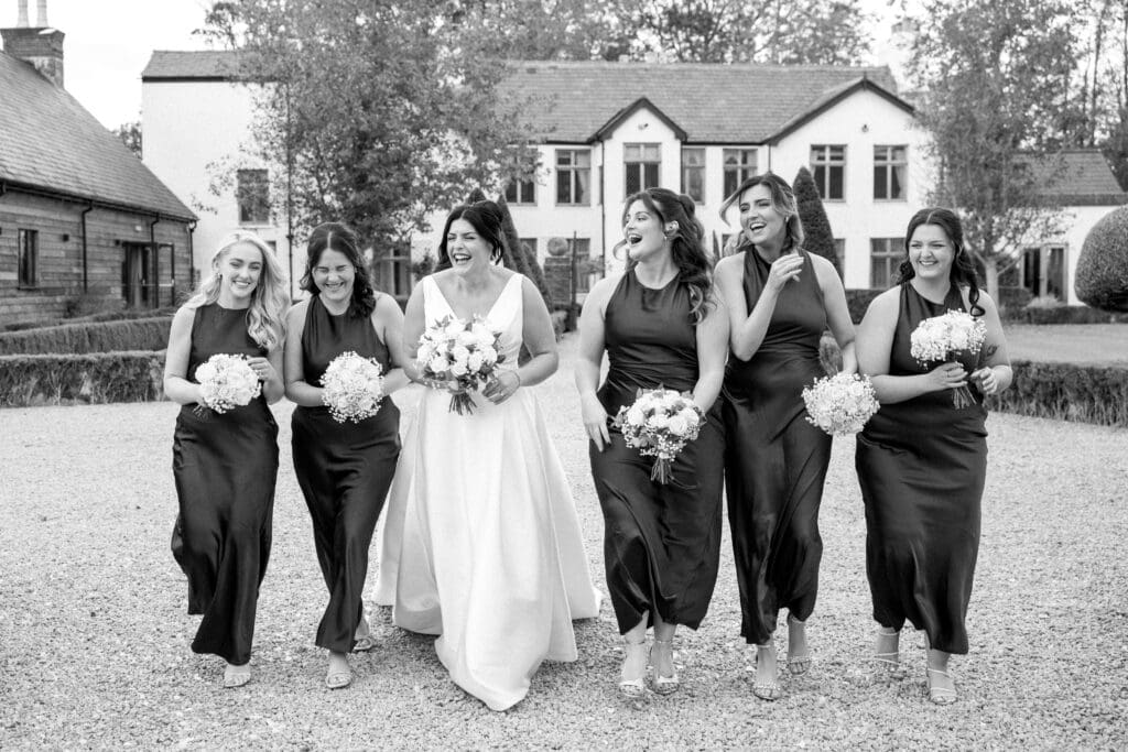Black and white portrait of the bridesmaids walking towards the camera and laughing at each other, taken by Victoria J Photography on behalf of Nessworthy Pictures