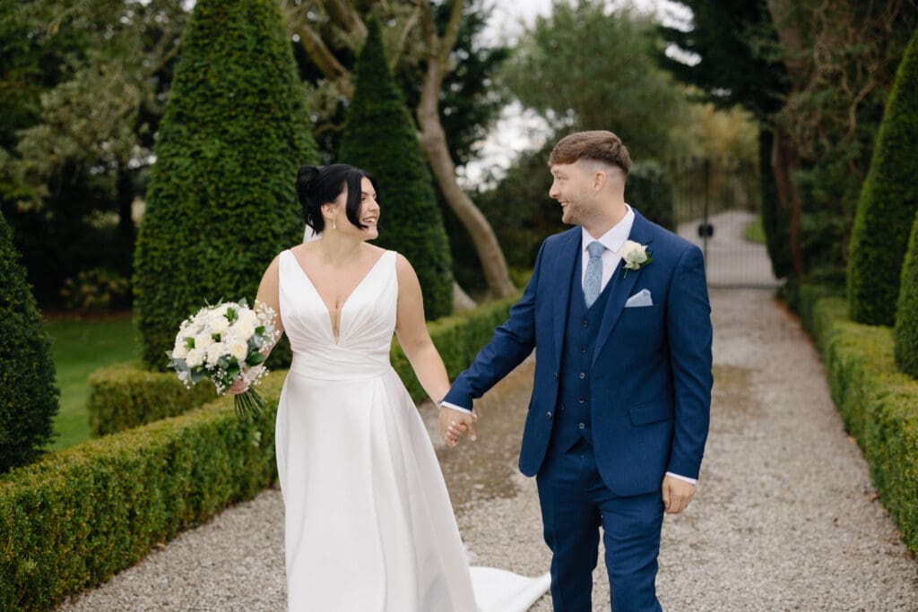 Portrait of the bride and groom walking hand in hand down the pathway at the River Barn, Poulton-le-Fylde, by Nessworthy Pictures