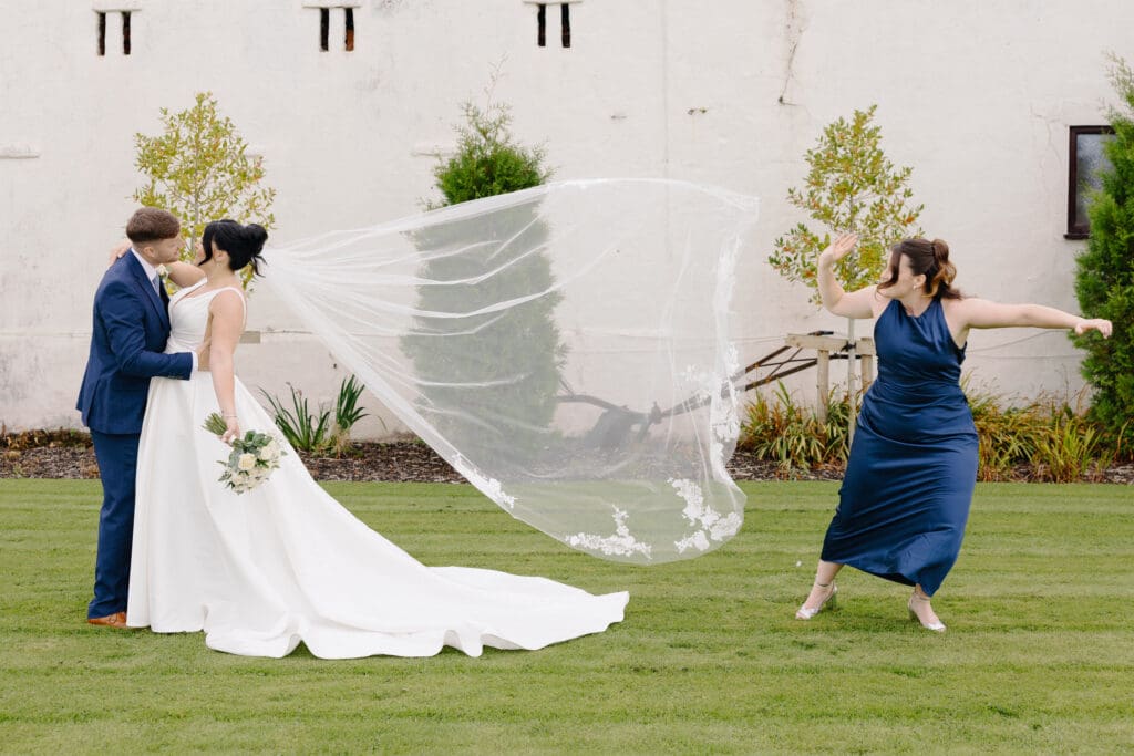 Bridesmaid runs out of shot after flapping the bride's veil into the air