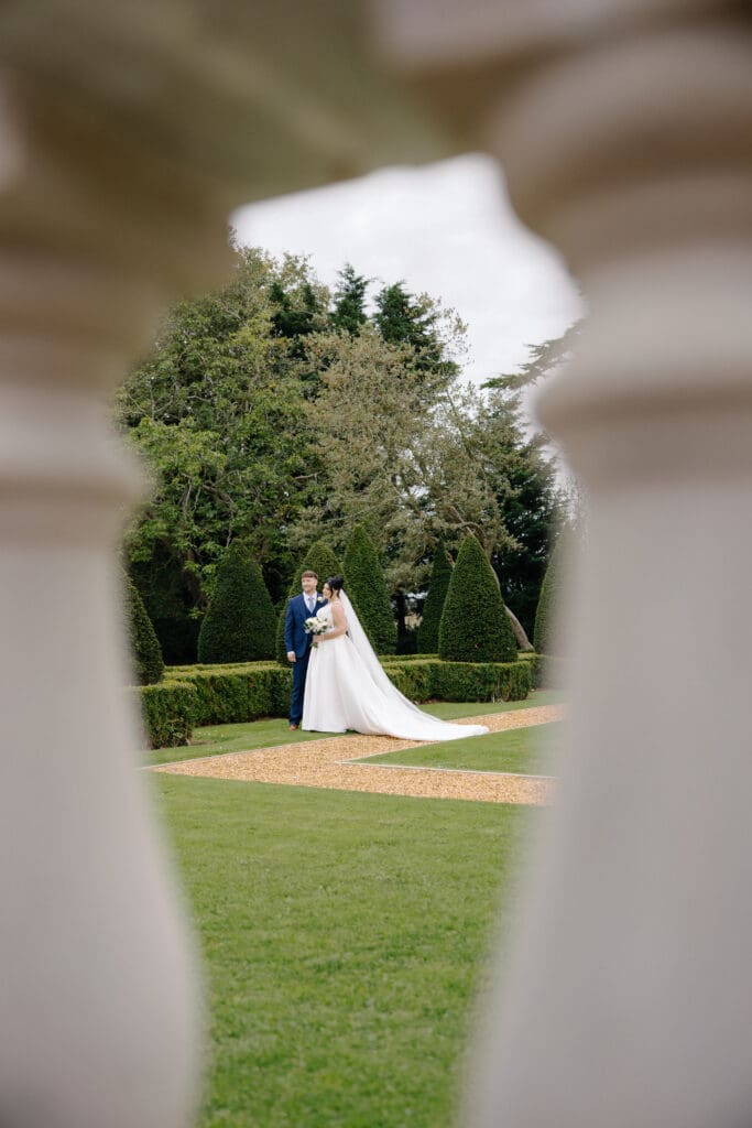 Portrait of the bride and groom shot between foreground pedestals, taken by Victoria J Photography on behalf of Nessworthy Pictures