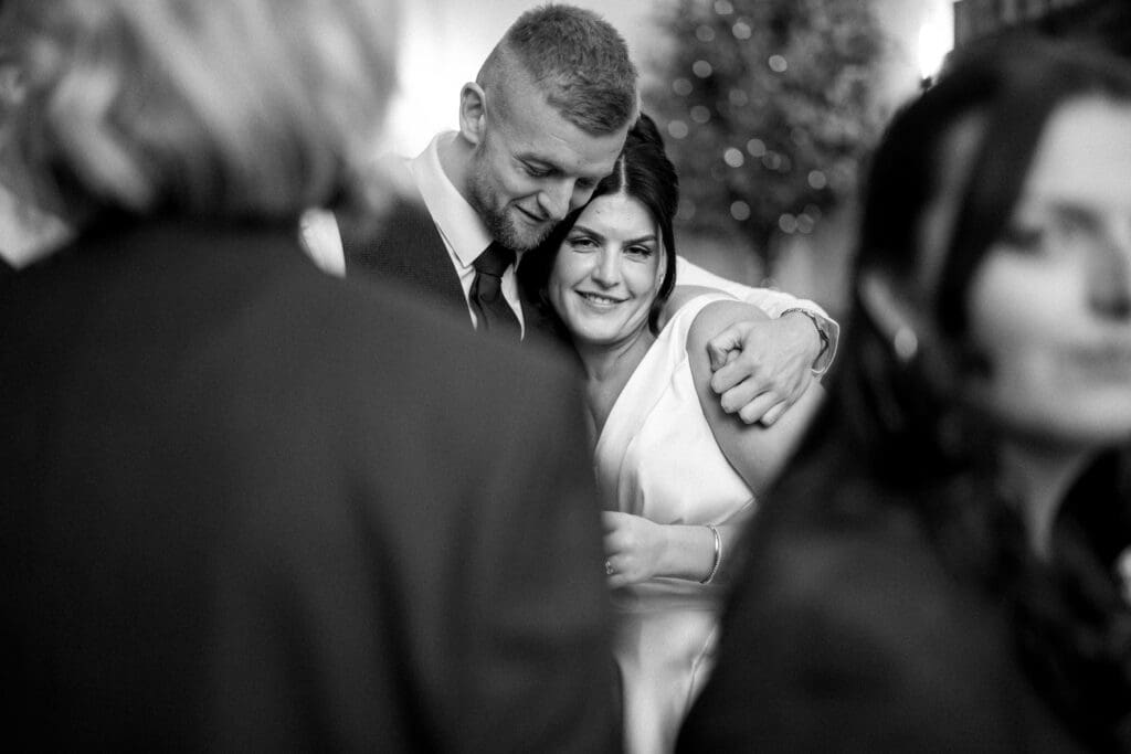 Groomsman hugs the bride, black and white photography at the River Barn, by Lancashire wedding photographer Bill Nessworthy