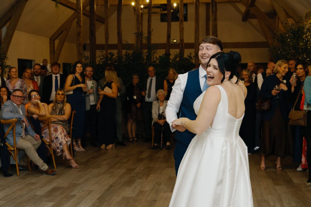 Bride and groom laugh during their first dance at the River Barn