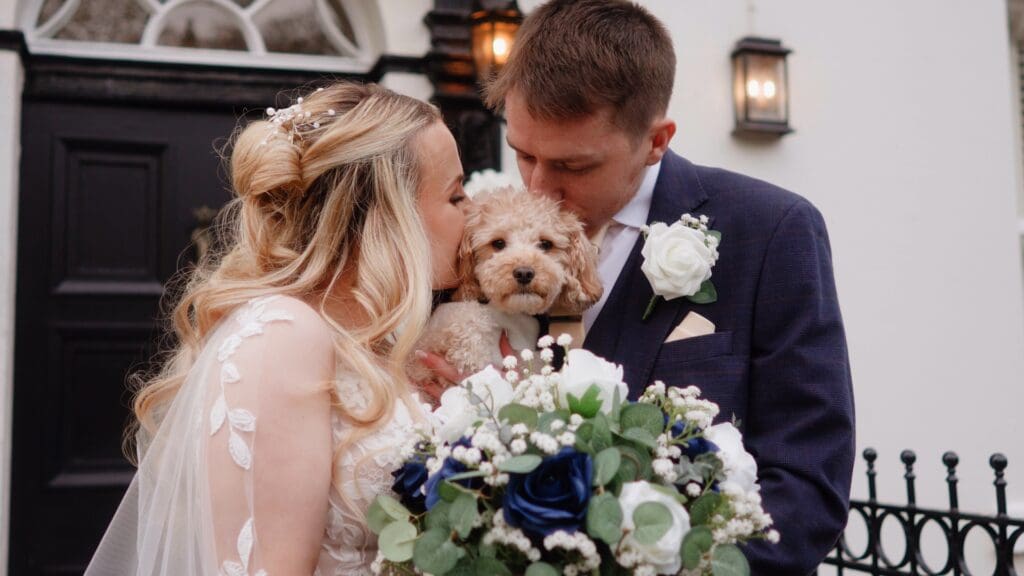 Bride and groom kiss their yorkiepoo dog at their wedding at Sparth House, by Lancashire wedding videographer Bill Nessworthy