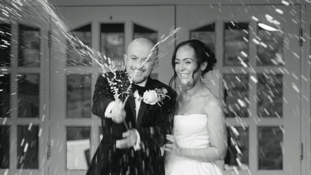 Bride and groom spray champaign, filmed by Shireburn Arms wedding videographer, Nessworthy Pictures